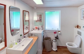 Ein Badezimmer mit Waschbecken, Spiegel, Toilette und Fenster.
