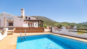 A rooftop pool with a clear view of the surrounding landscape, including a hill and a building with a white facade and a chimney. - Stunning home in Periana (Periana)