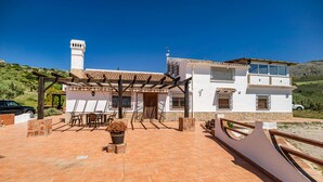 A white villa with a tiled patio, a pergola, and a view of the countryside. - Stunning home in Periana (Periana)
