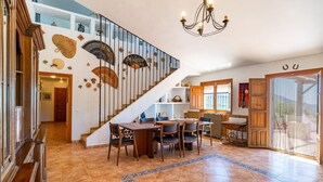 A spacious living area with a staircase, dining table, and chairs. - Stunning home in Periana (Periana)