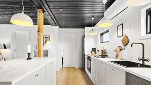 A modern kitchen with white cabinetry, a wooden floor, pendant lights, and a black ceiling. - 4 bedroom beautiful home in Humble (Humble)