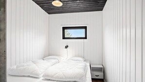 A bedroom with a bed, a nightstand, a wall-mounted lamp, and a window with a view of trees. - 4 bedroom beautiful home in Humble (Humble)