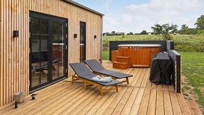 A wooden deck with two lounge chairs, a hot tub, and a grill. - 4 bedroom beautiful home in Humble (Humble)