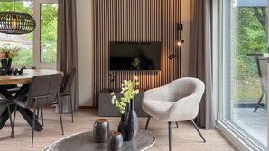 Un salon moderne doté d’un téléviseur, de sièges confortables et d’un coin repas.