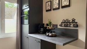 Une cuisine moderne dotée d’une machine à expresso intégrée, d’une décoration murale sur le thème du café et d’un porte-tasses.