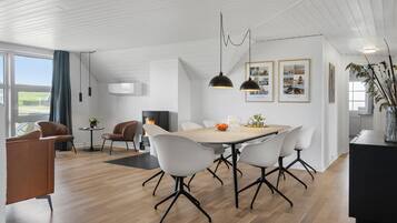 A modern dining area with a wooden table, white chairs, and pendant lighting.