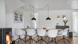 A modern dining area with a wooden table, white chairs, and a black pendant light.
