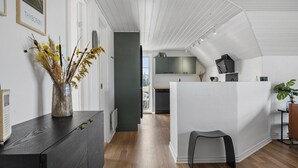 A modern kitchen with a white island, wooden flooring, and a view to the dining area.