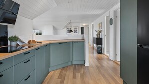 A modern kitchen with light blue cabinets, a wooden countertop, and a black refrigerator.