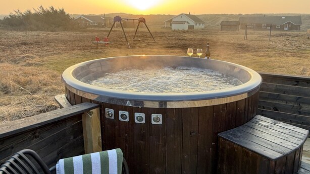 A hot tub on a wooden deck with a view of houses in the background.