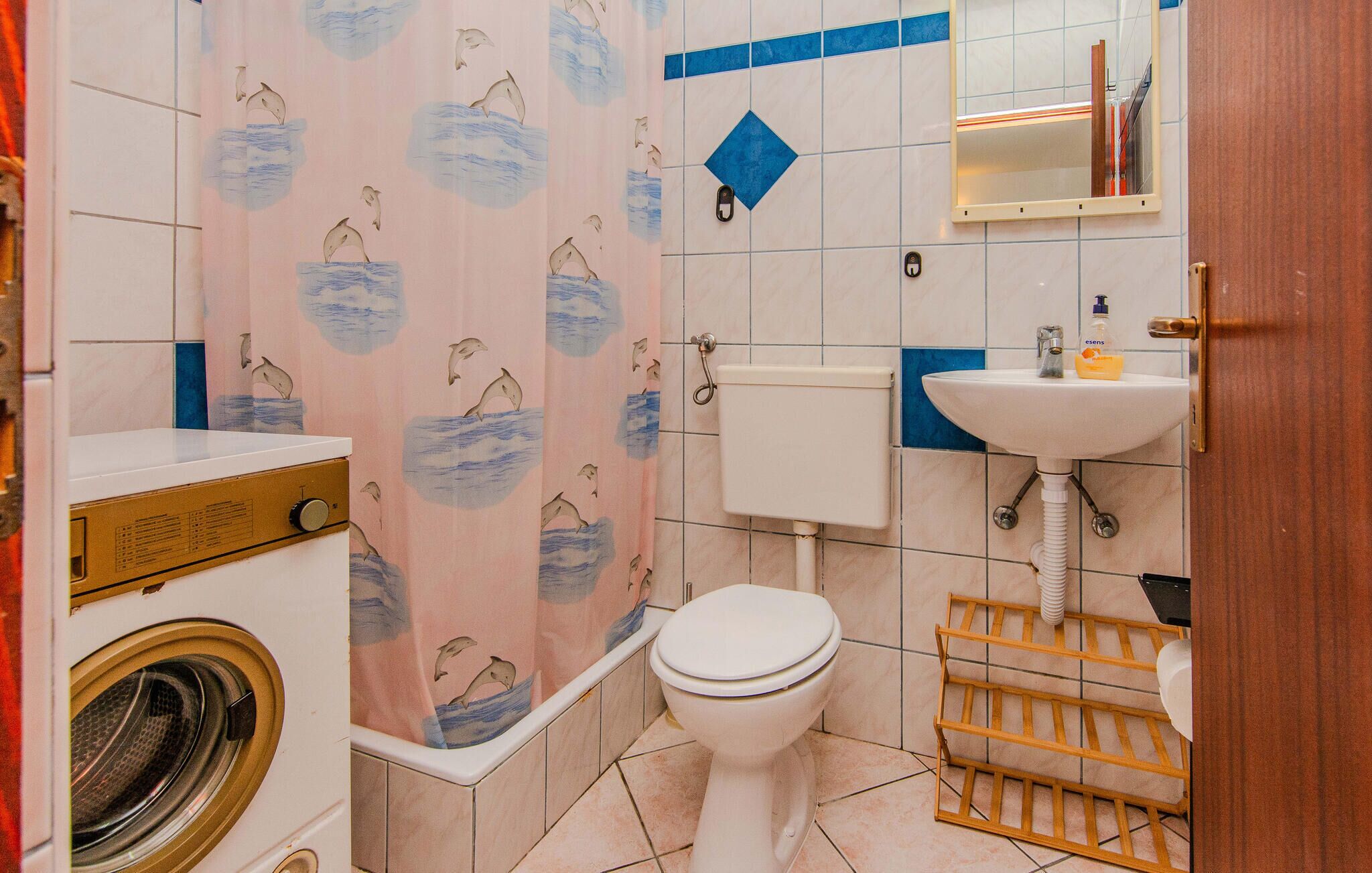Een kleine badkamer met toilet, wastafel en wasmachine.