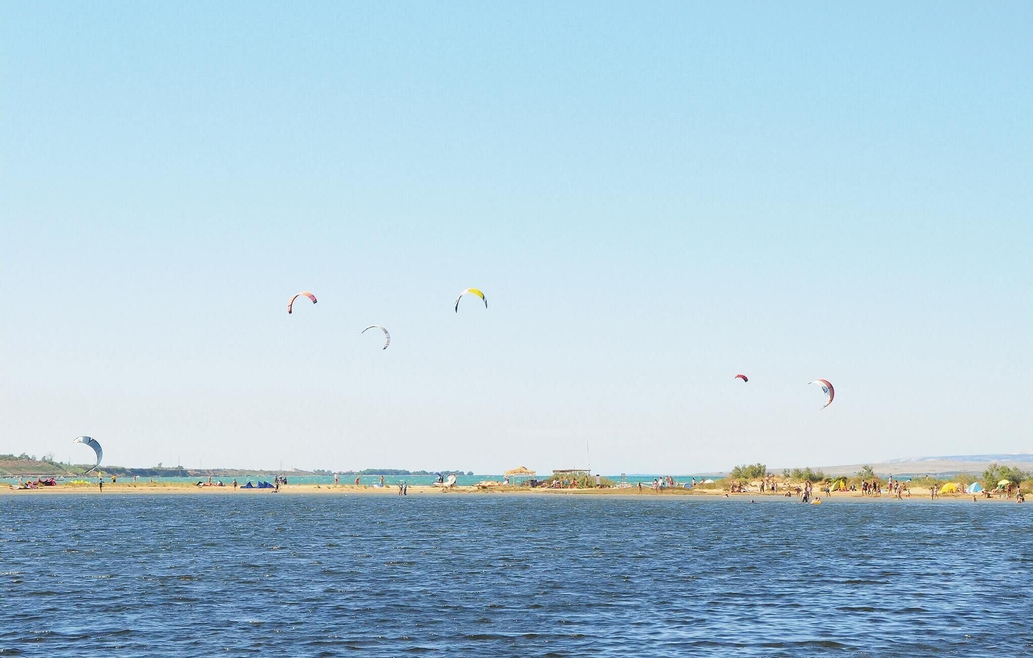 A beach with people and kites flying.