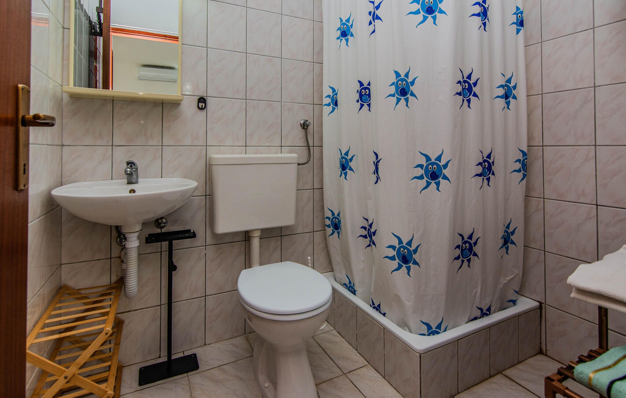 Un baño con inodoro, lavamanos y cortina de ducha con estampado azul.