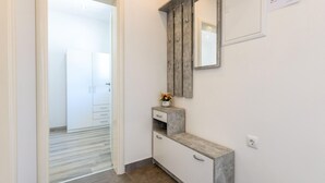 A hallway with a wooden bench, a small table with a vase of flowers, and a mirror on the wall. - Lovely apartment in Ploce with WiFi (Ploce)