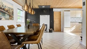 Un área de comedor moderna con una mesa de madera y sillas de cuero, una pared de acento negra y un cuadro con una vista urbana.