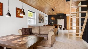 Una sala de estar acogedora con techo de madera, un sofá, una mesa de centro y una chimenea.