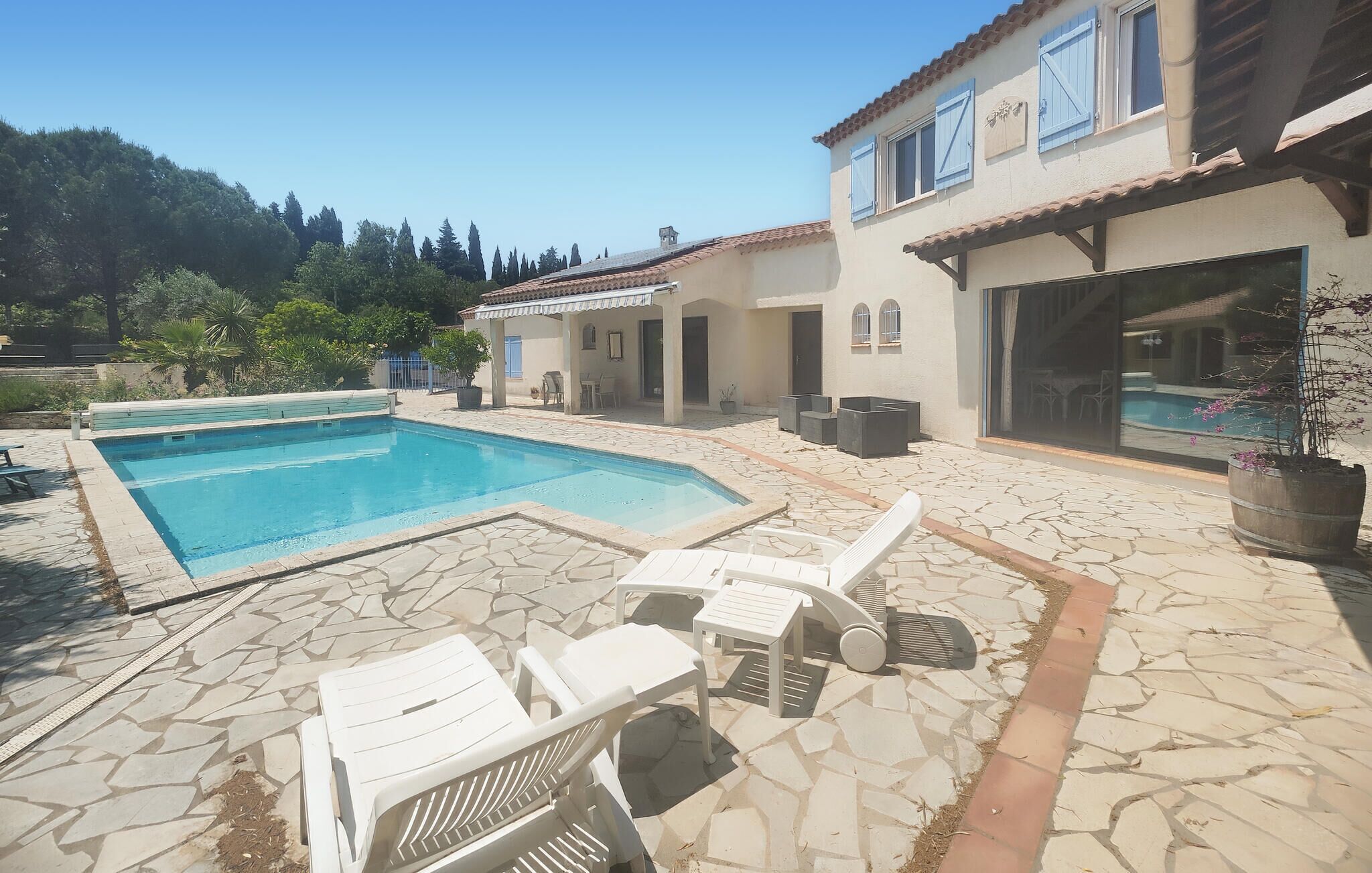 A swimming pool with lounge chairs and a stone patio.