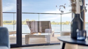 A balcony with a wooden chair and a table, overlooking a body of water and greenery. - 2 bedroom gorgeous home in Kerkdriel (Kerkdriel)