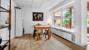 Un comedor con una mesa y sillas de madera, vistas al exterior a través de amplios ventanales y un mapa colgado en la pared.
