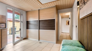 Un interior moderno con una puerta corredera que da a un espacio exterior, un banco y un cuadro en la pared.