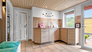Una cocina moderna con armarios de madera, salpicadero de azulejos y ventana con vista a la vegetación.
