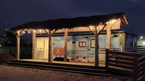 A beachside structure with a thatched roof, wooden pillars, and a small pool area. - Blackwater Bay beach tiny homes (Bolivar Peninsula)