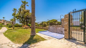 A pool area with stone walls and a tiled deck, surrounded by a fence and palm trees. - Awesome home in Tarifa with outdoor swimming pool (Tarifa)