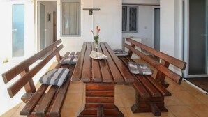 A dining area with wooden benches and a central table, featuring a vase with flowers.