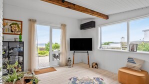A spacious living room with a large window, a flat-screen TV, and a wooden ceiling. - Nice home in Ebeltoft with WiFi (Ebeltoft)