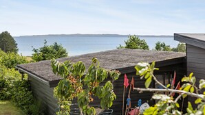 A wooden cabin with a view of the sea, surrounded by greenery. - Nice home in Ebeltoft with WiFi (Ebeltoft)