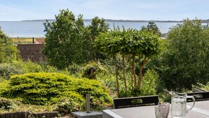 A terrace with a view of the sea, surrounded by lush greenery and a wooden fence. - Nice home in Ebeltoft with WiFi (Ebeltoft)