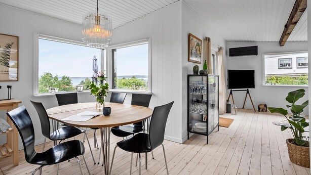 A dining area with a round table, black chairs, a chandelier, and a view of the outdoors. - Nice home in Ebeltoft with WiFi (Ebeltoft)