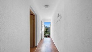 A narrow hallway with white walls and a tiled floor, leading to an outdoor area with a table and chairs. - One bedroom cozy apartment in Betina (Betina)