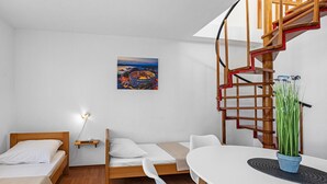 A compact room with a bed, a small sofa, a dining table, and a spiral staircase. - One bedroom cozy apartment in Betina (Betina)