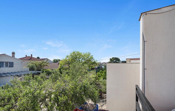 A residential area with a white building, a tree, and a clear blue sky.