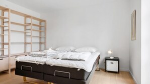 Ett modernt sovrum med en säng, ett sängbord, en lampa och en inbyggd hyllsektion.