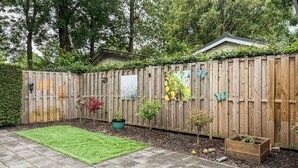 A wooden fence with various decorations, a green lawn, and a raised garden bed. - 2 bedroom nice home in Ochten (Ochten)