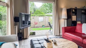 A living room with a TV, red sofa, and a coffee table. - 2 bedroom nice home in Ochten (Ochten)