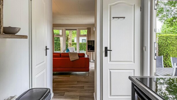 A hallway leading to a living area with a red sofa, wooden flooring, and a white door. - 2 bedroom nice home in Ochten (Ochten)
