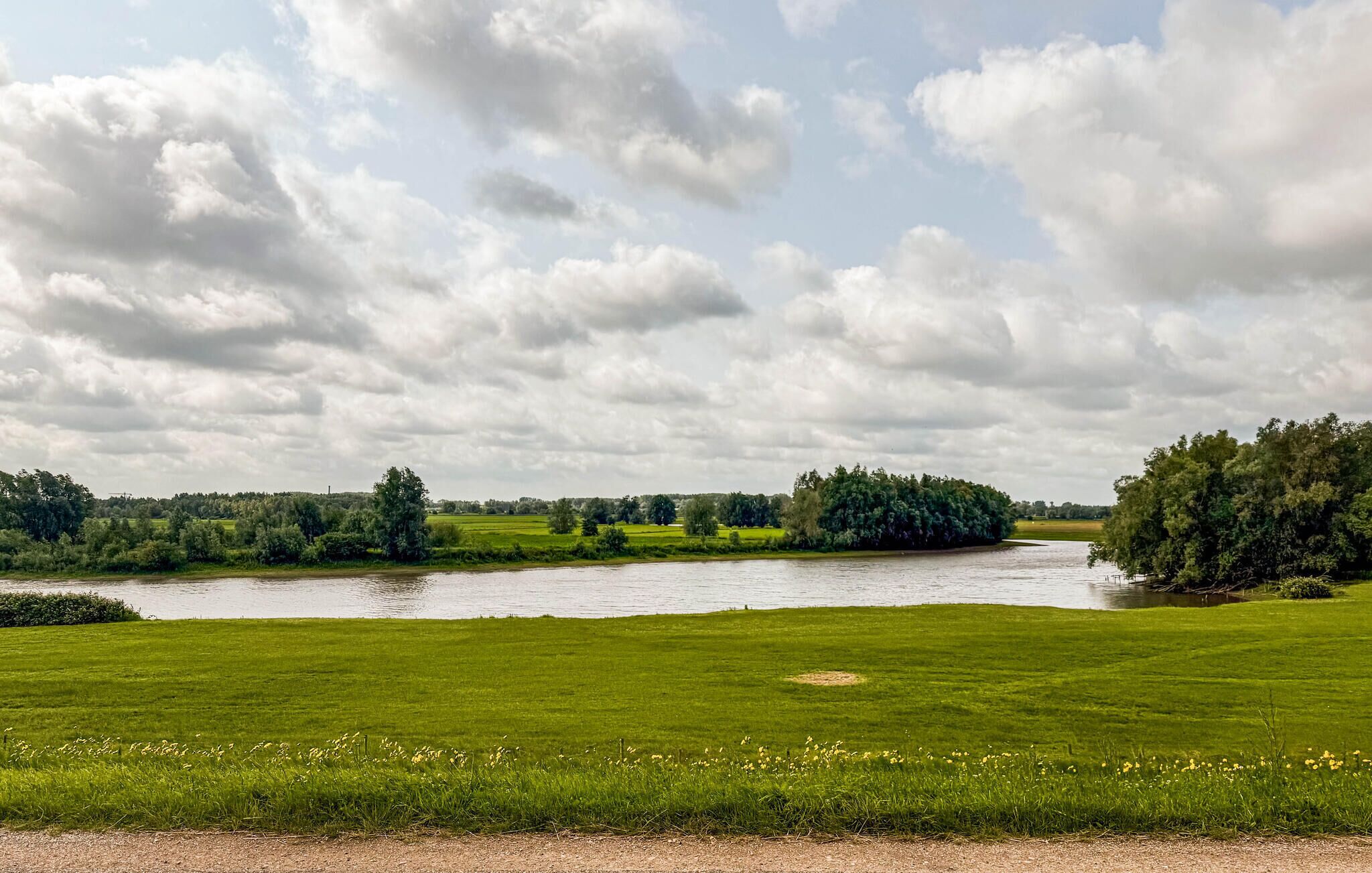 Ein Fluss fließt durch eine grüne Landschaft mit Bäumen und offenen Feldern.