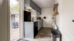 A compact kitchen with grey cabinets, a stainless steel range hood, and a small island with a sink. - 2 bedroom nice home in Ochten (Ochten)