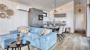 Un salon moderne avec un canapé bleu, une table à manger et une cuisine en arrière-plan.