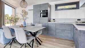 Une cuisine moderne avec des meubles gris, un îlot central et un coin repas avec des chaises grises.