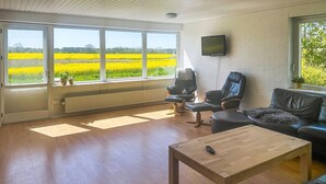 Un salon spacieux doté de grandes fenêtres, d’une table basse en bois et de sièges en cuir.