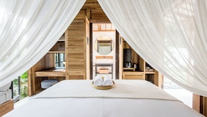 Ein Schlafzimmer mit einem Bett, einem Holztisch, einem Spiegel und einer Kaffeemaschine.