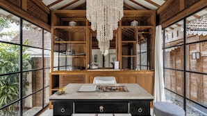 Ein Zimmer mit Holzvertäfelung, großen Fenstern, einer Chandelierleuchtre und einem Tisch mit einer Zeitschrift.