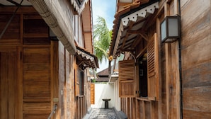 Un étroit couloir en bois, avec un chemin pavé de pierres, des portes en bois et des éléments architecturaux traditionnels.
