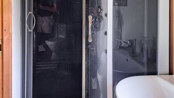 A bathroom with a glass shower enclosure, a white sink, and a toilet.