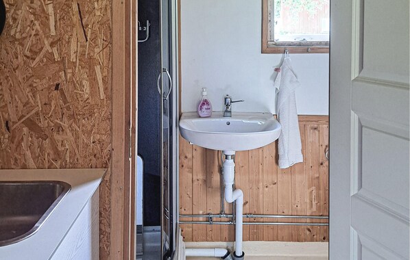 A bathroom with a wooden wall, a white sink, a window, and a towel hanging on the wall.
