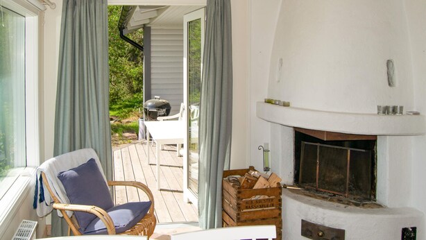 A cozy outdoor seating area with a wicker chair, a fireplace, and a wooden crate. - Amazing home in åkersberga with WiFi (Åkersberga)